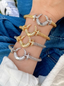 Detail of horse-shoe buckle bracelets in gold and silver with sparkling zircon pavé