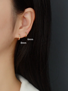 Detail showing 6mm and 8mm gold huggie earrings with rainbow stones on ear