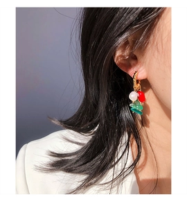 Detail of twisted gold earrings featuring natural pearls and colorful gemstone beads