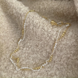Close-up of a double-layered 925 silver beaded necklace on beige plush fabric