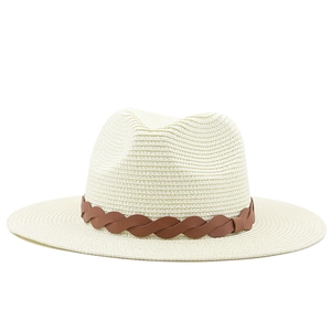 Detail of cream woven straw hat featuring a stylish brown decorative band and flat brim