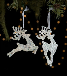 Sparkling silver reindeer ornaments with sequins hanging on a green Christmas tree branch