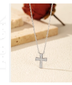 Close-up of S925 sterling silver cross necklace with pavé moissanite on a stone background
