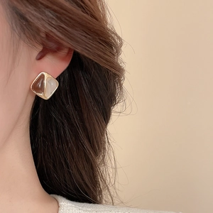 Gros plan de boucles d'oreilles géométriques en résine marron et crème avec bord doré
