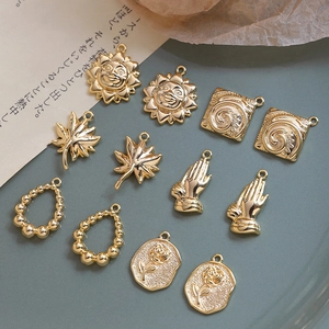 Detailed close-up of assorted gold-plated vintage sun, leaf, and rose charms for DIY jewelry