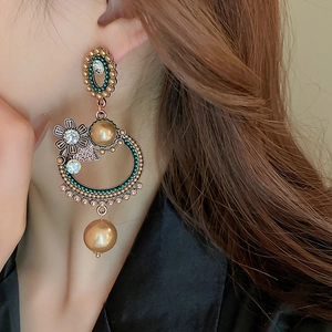 Close-up of vintage gold floral earrings with green beads and champagne pearls on a model