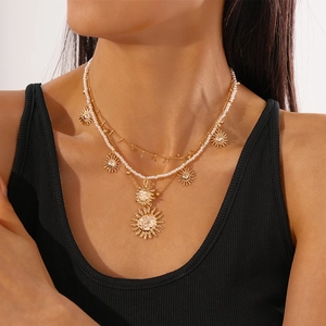 Detailed view of triple-layered gold sun pendant necklace with imitation pearls