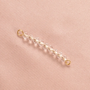 Macro shot of stainless steel gold connector with faceted clear crystal birthstone beads
