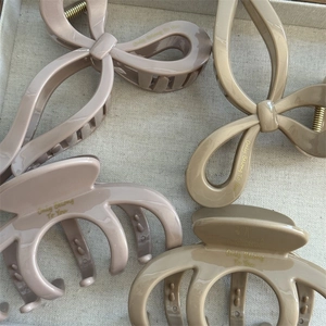 Detailed view of beige and khaki glossy hair claws with Only Belong to You gold text