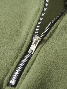 Macro detail of silver metal zipper and soft grass green coral fleece fabric texture