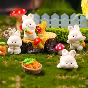 Macro shot of miniature white resin rabbits with carrots and mushrooms in a fairy garden