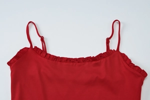 Detail of red camisole top featuring ruffled neckline and adjustable thin shoulder straps