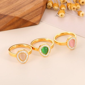 Detailed macro view of three gold-plated teardrop rings with pink, green and champagne stones