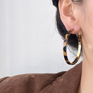 Close-up of model wearing large leopard print earrings with gold-tone metal trim