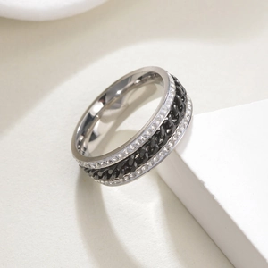 Détail de la chaîne noire rotative et de la double rangée de zircons sur la bague en acier