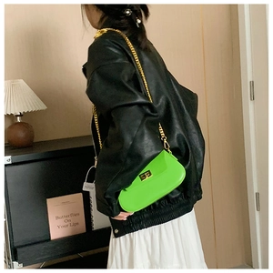 Detail of neon green crossbody bag with gold chain and metal twist lock on a model
