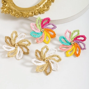 Detailed close-up of handmade raffia flower earrings with woven textures and gold center beads