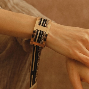 Wide hollow stainless steel bangle with H-shaped buckle and woven textured inlay
