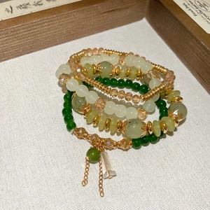 Detailed macro view of four-layer beaded bracelets with green crystals and gold charms