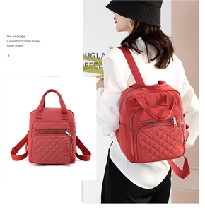 Detail of red quilted nylon backpack with multiple pockets and adjustable straps