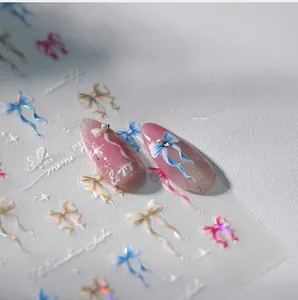 Macro shot of 3D bow nail stickers with laser effect and pearls on pink gradient nails