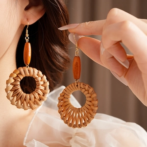 Détail de boucles d'oreilles bohèmes en rotin rond avec perles en bois sur modèle