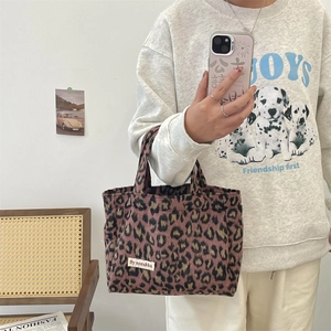 Detailed macro view of the leopard print tote bag with a white woven logo tag on front