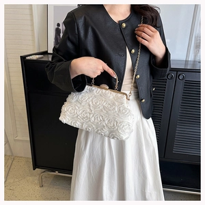 Close-up of white evening bag featuring 3D floral textures and elegant gold chain strap