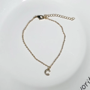 Close-up of golden letter C pendant bracelet with zircon inlay on a white plate