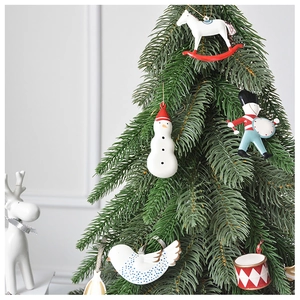 Detailed view of hand-painted ceramic Christmas ornaments hanging on pine tree branches