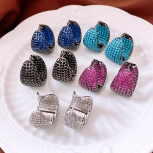 Macro shot of five pairs of colorful huggie hoops with zircon pave on a ceramic plate