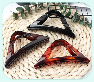 Close-up of three triangle claw clips in black and amber colors on a textured mat