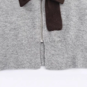 Women's loose grey knit hoodie with ribbon bow and silver zipper closure details