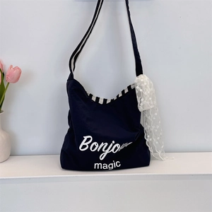Detail of navy canvas tote bag with Bonjour magic print and striped woven strap