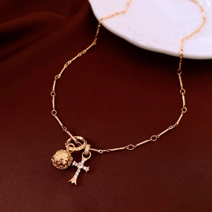 Detailed close-up of a vintage gold cross necklace with rhinestone and hollow metal ball