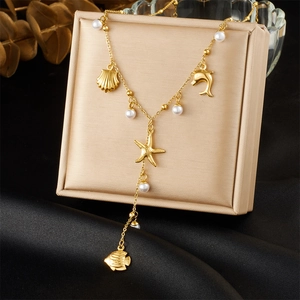 Detail of gold Y-shaped necklace with sea shells and pearls on a display box