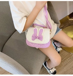 Girl wearing a purple and white rabbit ear crossbody bag with bow and quilted pattern