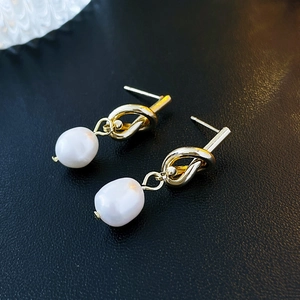 Gros plan détaillé de boucles d'oreilles nœud doré avec pendentifs perles baroques