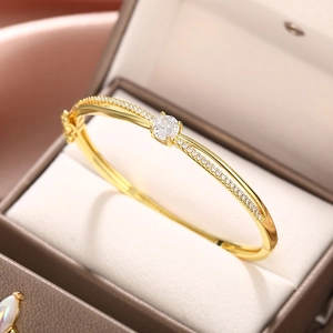 Detail of elegant gold crossover bracelet with round zircon and pavé diamonds in box
