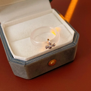 Detail of white chalcedony ring with silver cross pendant in a velvet jewelry box