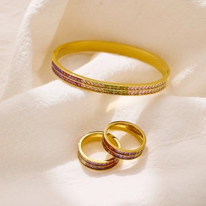 Set di gioielli in zircone arcobaleno con bracciale dorato e anelli su tessuto bianco