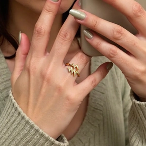 Close-up of a gold maple leaf ring with sparkling zircons worn on a model's finger
