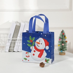 Blue Christmas non-woven tote bag with snowmen and holly pattern on festive desk