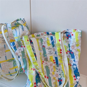 Détail de sacs cabas en coton avec motifs floraux colorés et étiquettes tissées