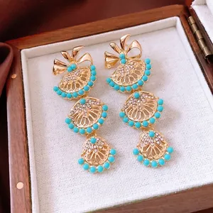 Boucles d'oreilles vintage dorées avec perles émeraude et cristaux sur boîte à bijoux