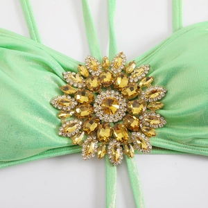 Close-up of mint green glitter bikini with a large golden sunburst crystal ornament