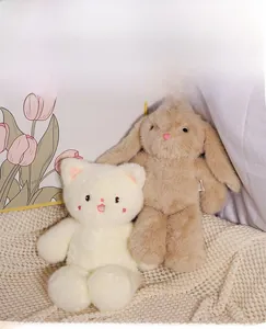Close-up of soft plush kitten and bunny dolls with fluffy textures on a knitted blanket