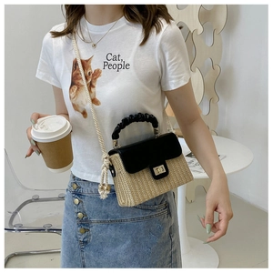 Detail of a woven straw mini bag featuring a black and white color block with rope strap