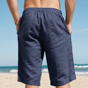 Rear view of deep blue linen shorts for men featuring elastic waist on a beach background