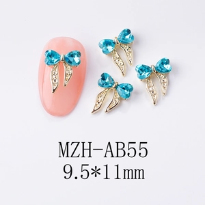 Détail du bijou d'ongle nœud doré 9,5x11mm avec strass cœur bleu clair et rubans
